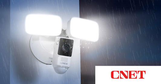 Lorex 2K Wi-Fi Floodlight Camera mounted outdoors in the rain, lights fully illuminated, featured in CNET’s roundup of the best home security cameras of 2026.