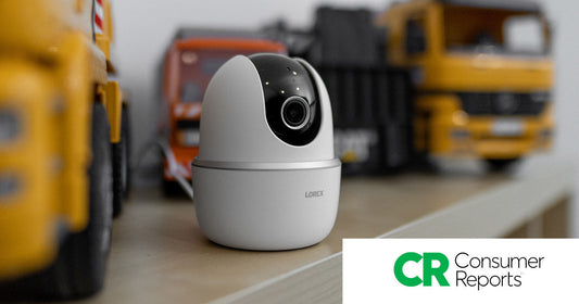 Lorex 2K Pan-Tilt Wi-Fi Camera placed on a shelf beside toy trucks, featured in Consumer Reports’ 2026 roundup of top-rated nanny cams.