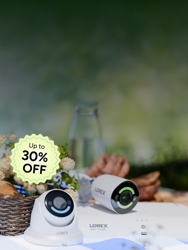 Lorex security cameras and 4K NVR on an outdoor picnic table with bread, flowers, and a spring setting in the background