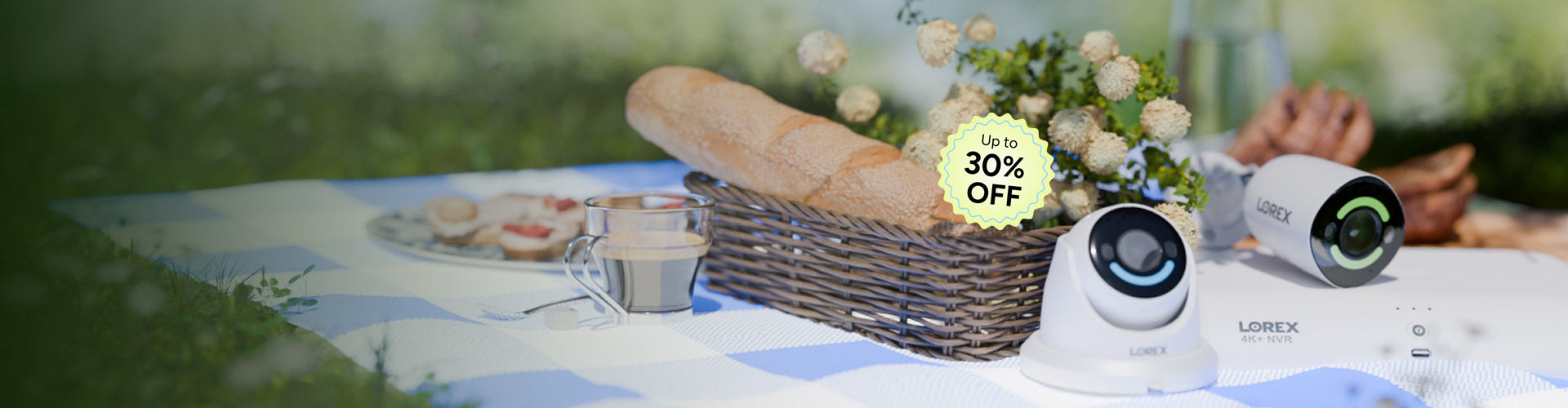 Lorex security cameras and 4K NVR on an outdoor picnic table with bread, flowers, and a spring setting in the background