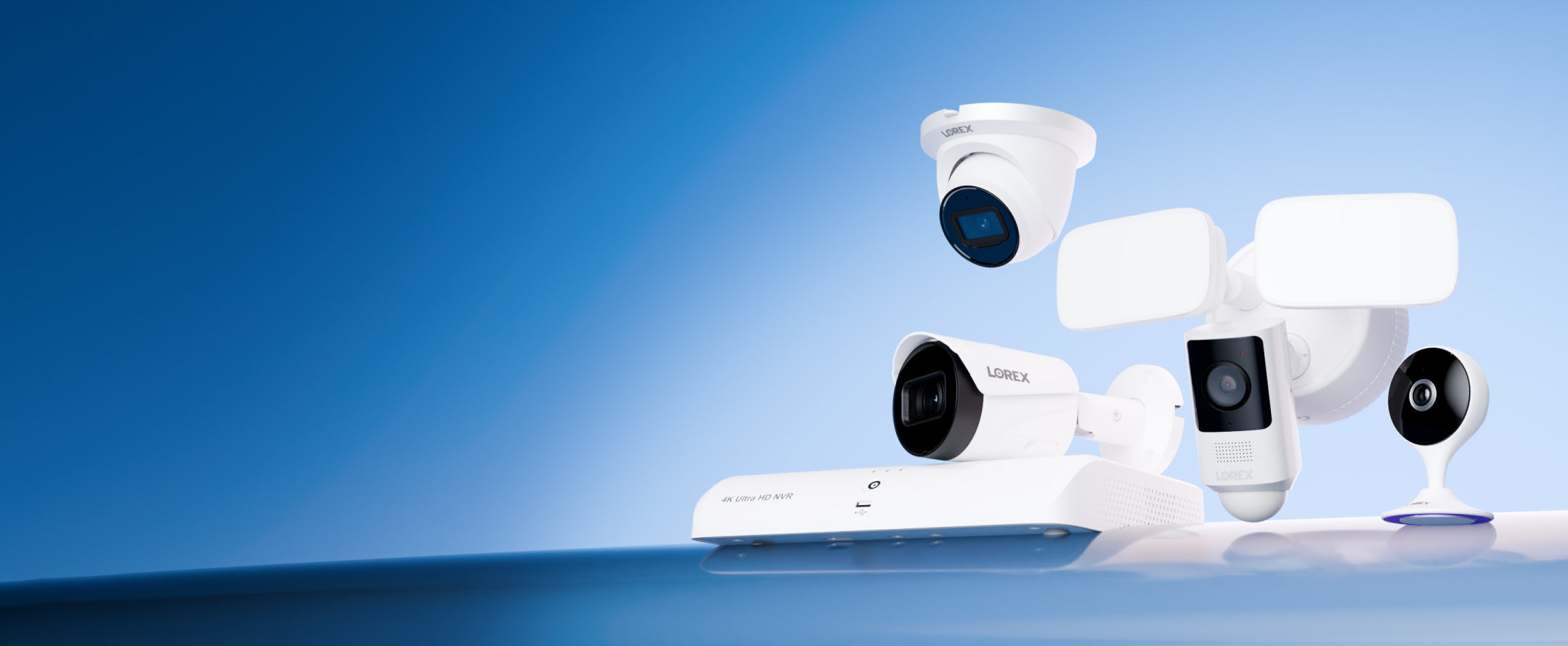 Group of Lorex security devices on a blue gradient backdrop, including a 4K NVR, outdoor IP camera, a floodlight security camera, and a compact indoor Wi-Fi camera.